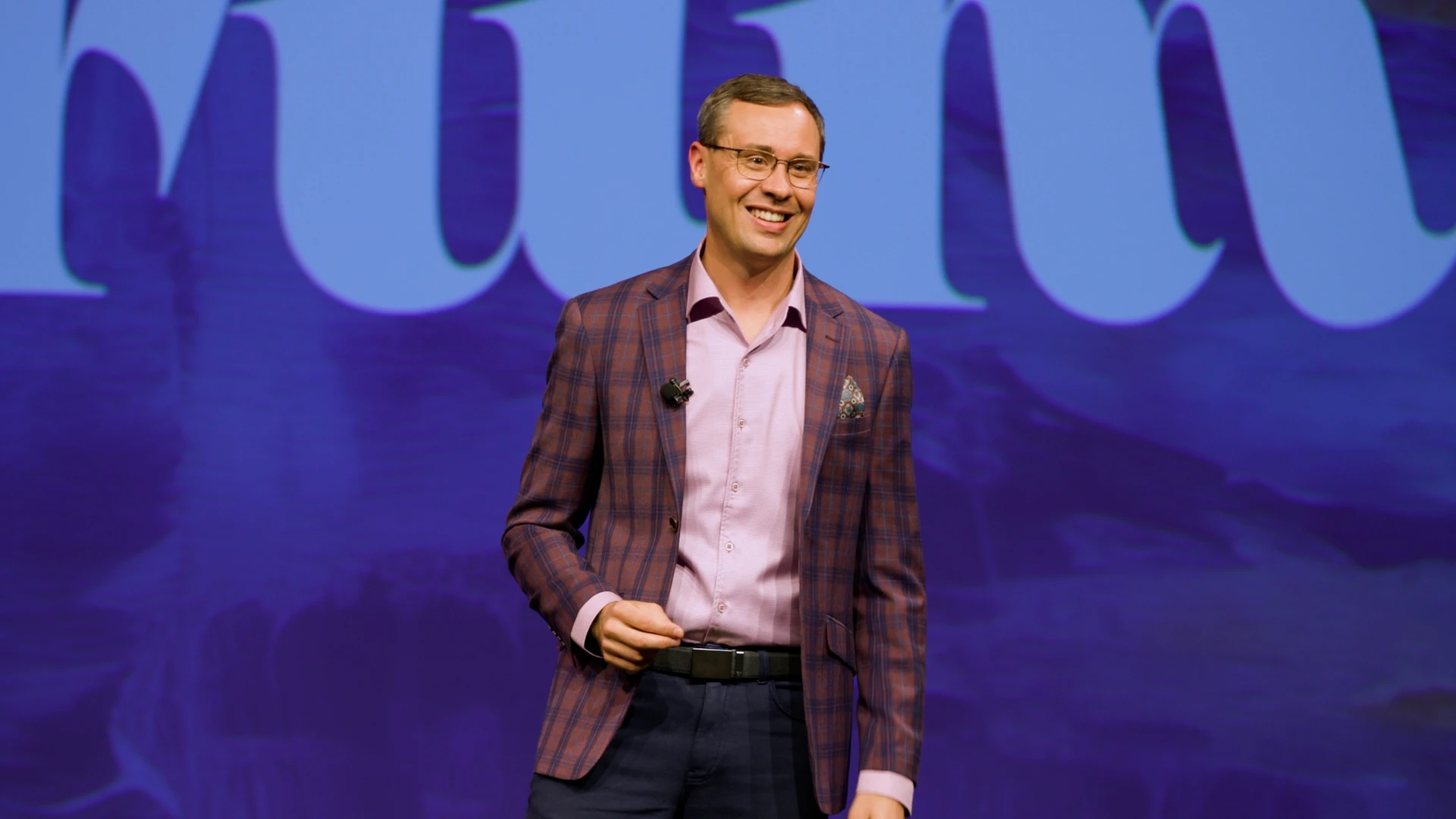 Joshua Berry smiling on stage during a keynote